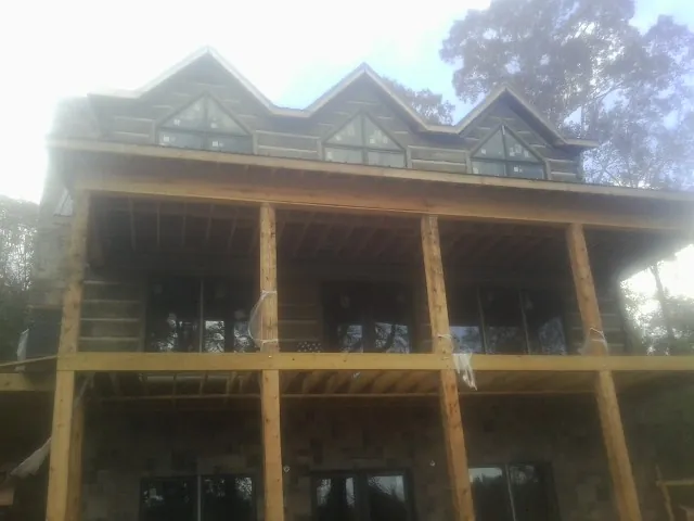 Dormers and porch framing on a large log home under construction — Roof Coating work by our crew in Lacrosse