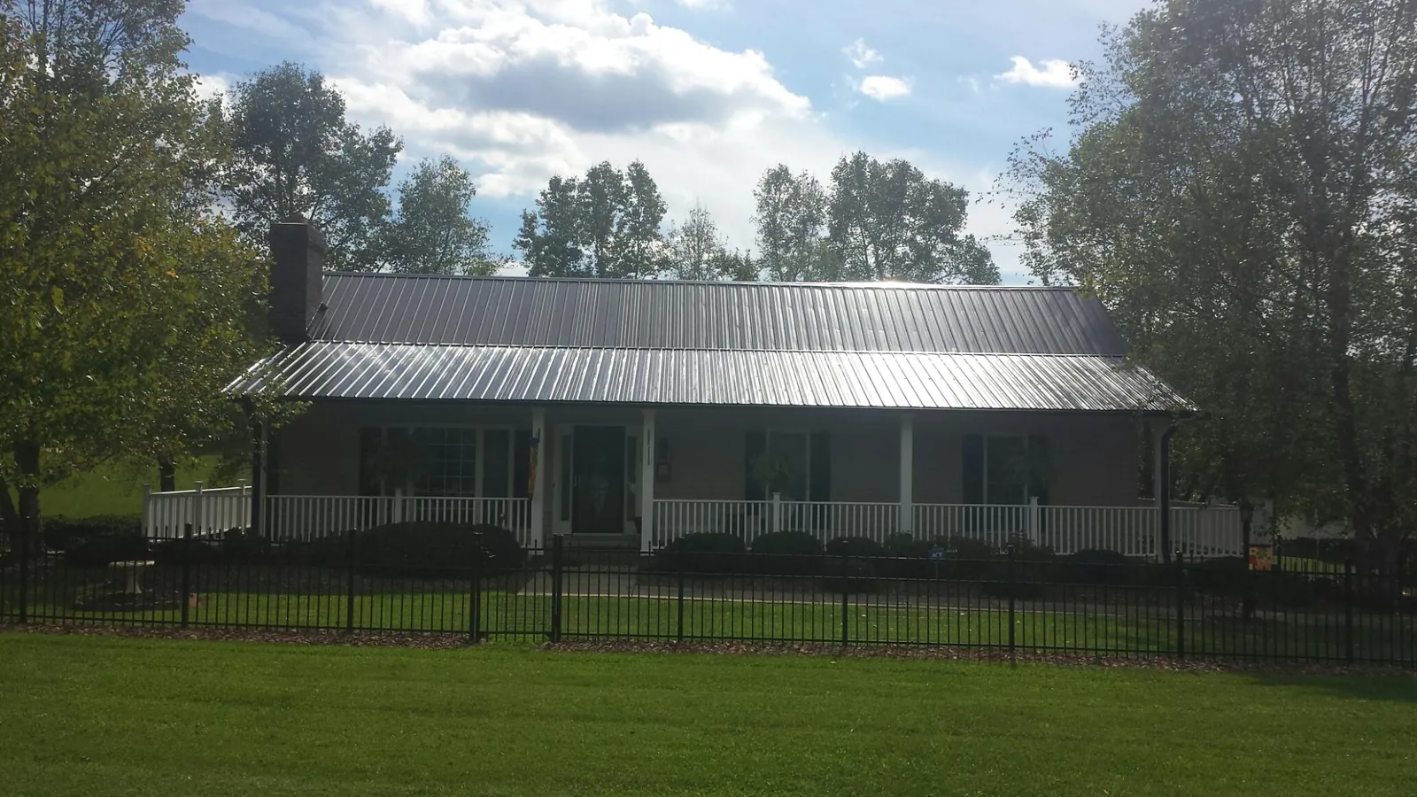 Gray metal roof on a brick ranch with a full width front porch — Gutter Guard Installation work by our crew in Lacrosse