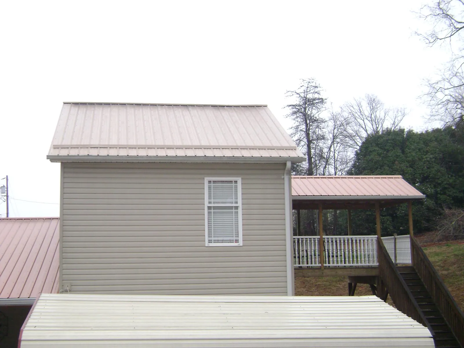 Tan metal roofs on a two story addition and attached porch, from a Roof Replacement job in Lacrosse