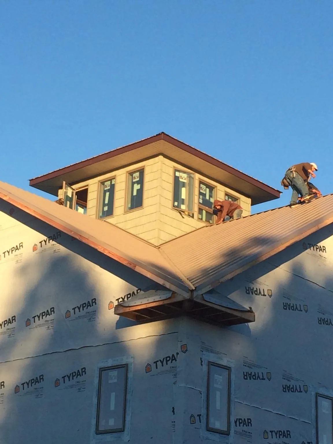 Roofers working around a rooftop cupola on a new metal roof at sunset — Roof Waterproofing in Lacrosse by Roofing Brothers